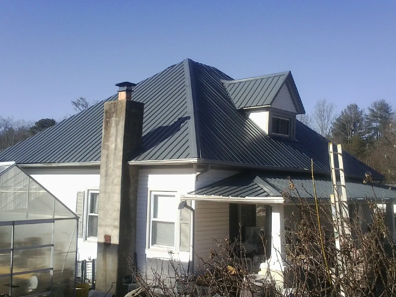 Dark blue standing seam metal roof on a white farmhouse with dormer — Slate & Tile Roof Repair by Roofing Brothers in Keosauqua
