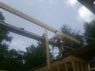 Carpenter setting a ridge beam over a new addition frame — Ice Dam Removal by Roofing Brothers in Keosauqua