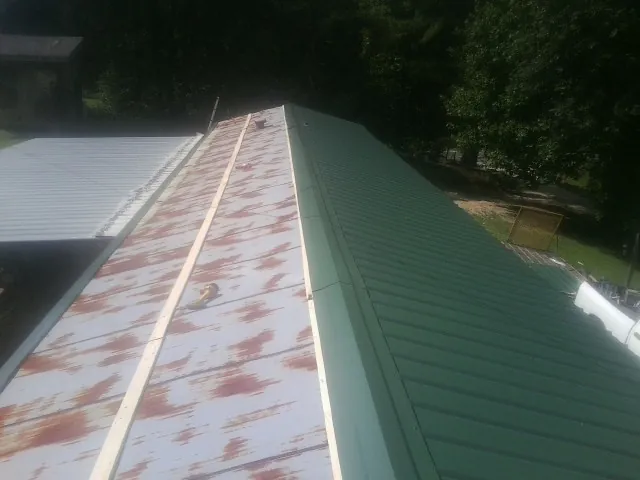 Old rusted panels beside newly installed green metal roofing — Wind Damage Roof Repair by Roofing Brothers in Keosauqua