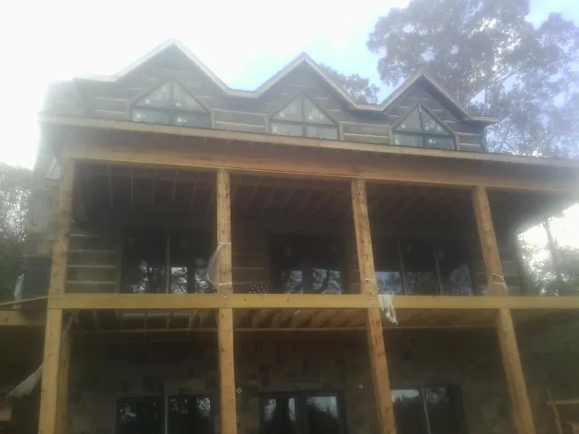 Dormers and porch framing on a large log home under construction — Roof Coating work by our crew in Keosauqua