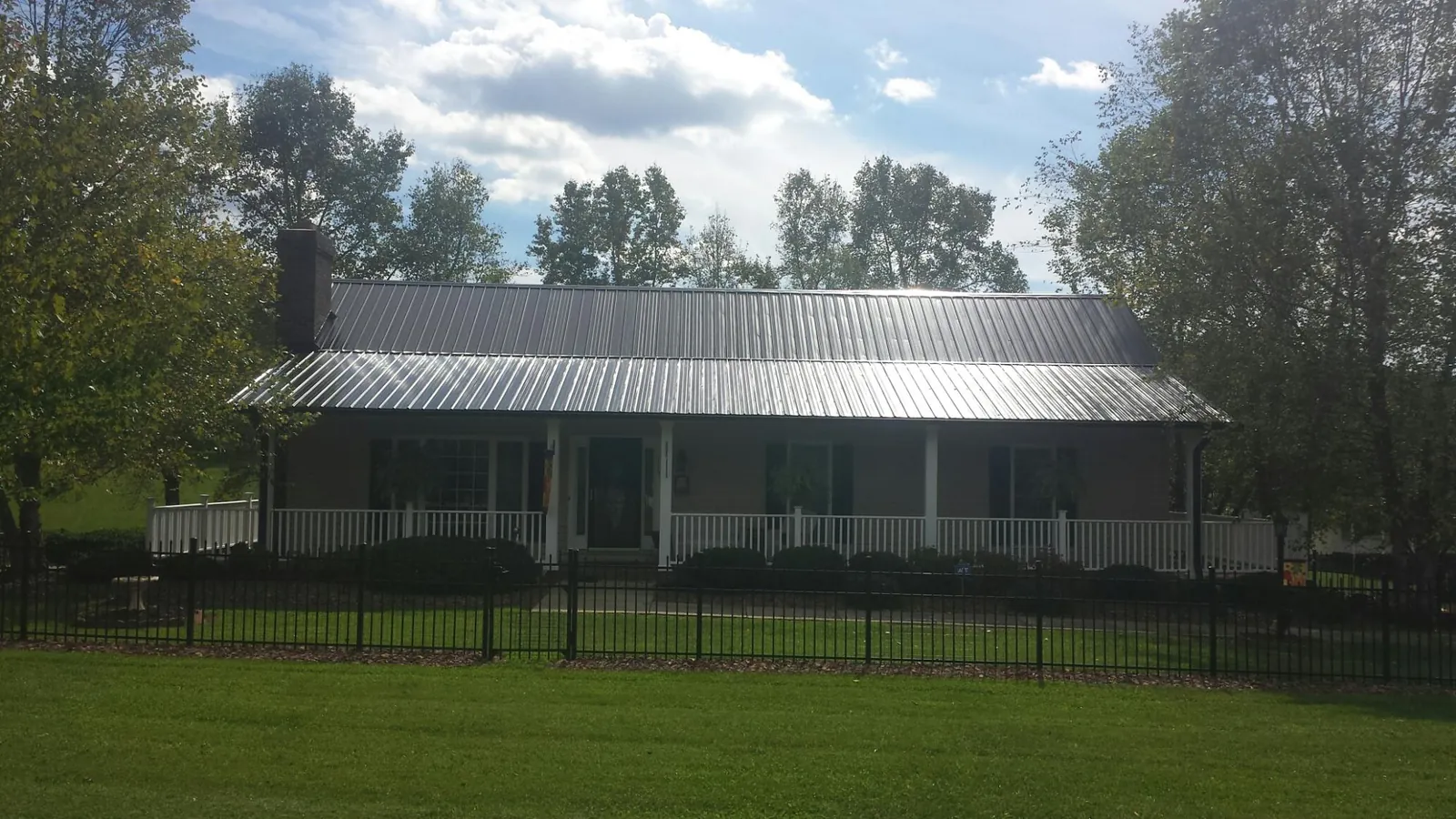 Gray metal roof on a brick ranch with a full width front porch — Gutter Guard Installation work by our crew in Keosauqua