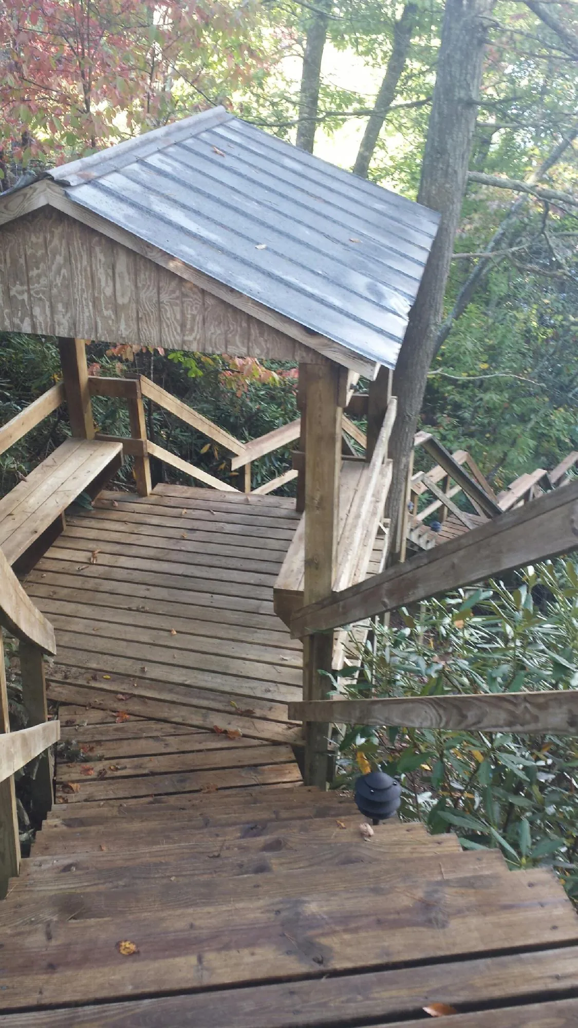 Metal roofed shelter over wooden steps on a wooded walkway — Skylight Repair & Installation work by our crew in Keosauqua