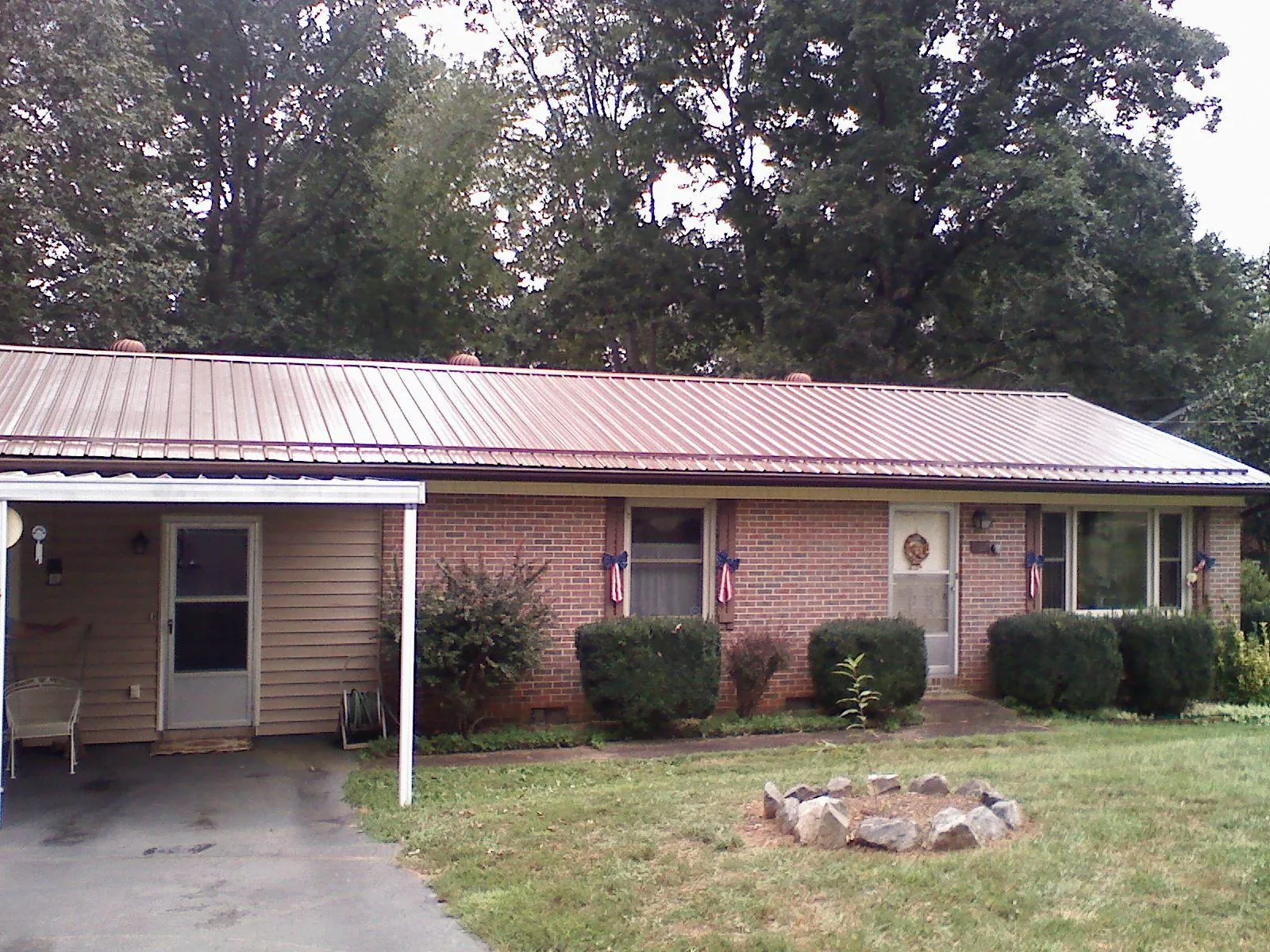 Bronze metal roof and carport on a brick ranch home — Roof Repair work by our crew in Keosauqua
