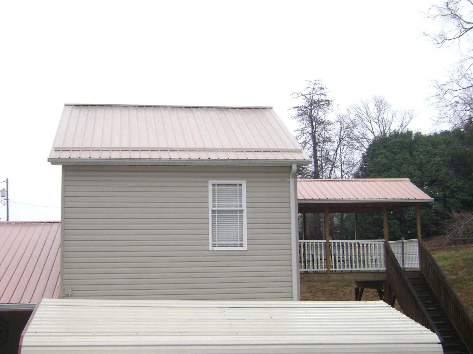 Tan metal roofs on a two story addition and attached porch, from a Roof Replacement job in Keosauqua