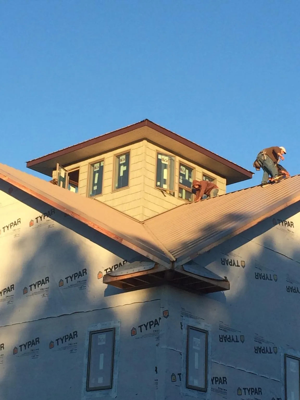 Roofers working around a rooftop cupola on a new metal roof at sunset — Roof Waterproofing in Keosauqua by Roofing Brothers